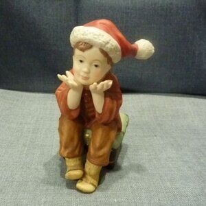 5 Inch Porcelain Boy sitting on a stool with a Christmas hat on.